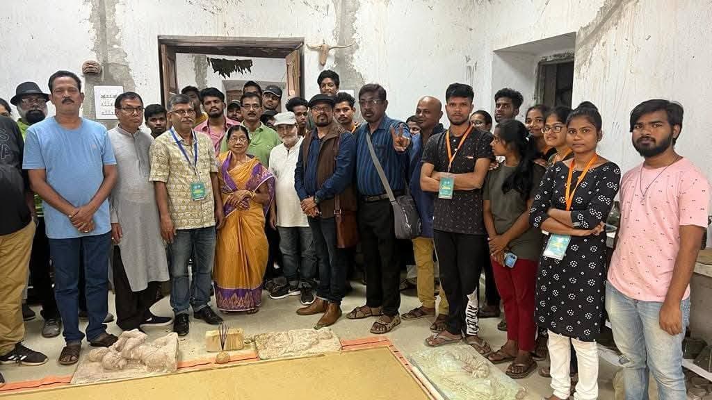 Basanta Kumari Samanta in a large group photo with participants at an art workshop, clay relief works laid out on the floor